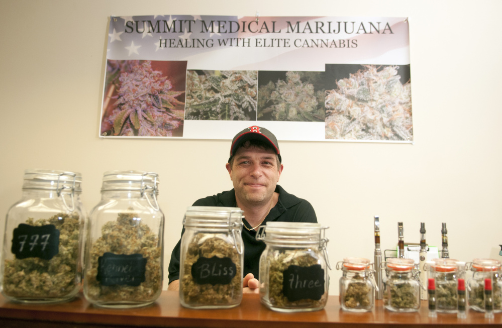 Dennis Meehan with some of the varieties of medical marijuana for sale on July 7 at the new Summit Medical Marijuana storefront on Water Street in Gardiner.