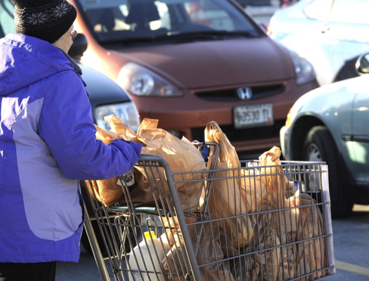 Grocery shoppers carry plastic bags Jan. 9, 2014, at a Hannaford supermarket in Portland.