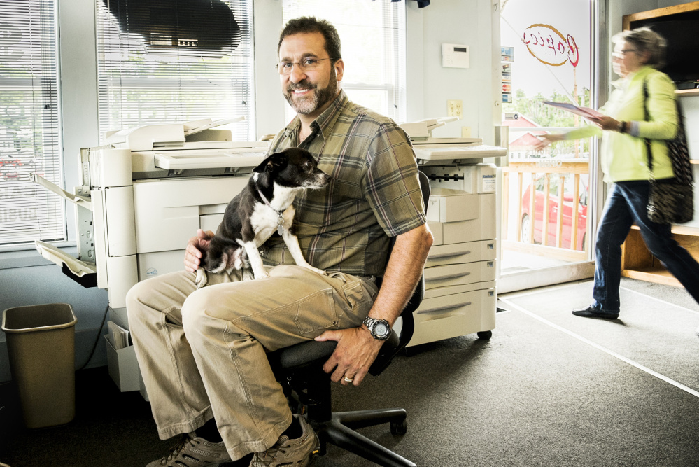 Joey, the dog, sits Monday on the lap of his owner, Larry Violette, at Copies Etc on U,S. Route 202 in Manchester. Joey provides friendly greetings to customers when they visit the family-owned business.