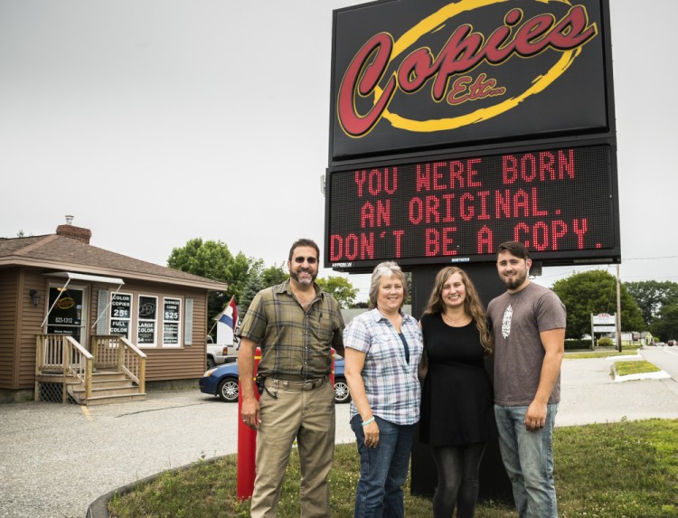 Members of the Violette family stand Monday in front of the Copies Etc electronic sign, known for quotations that entertain and inspire drivers on U.S. Route 202. The family members who work in the shop, from left, are Larry; his wife, Chrystal; daughter Ashley; and son Stephen.