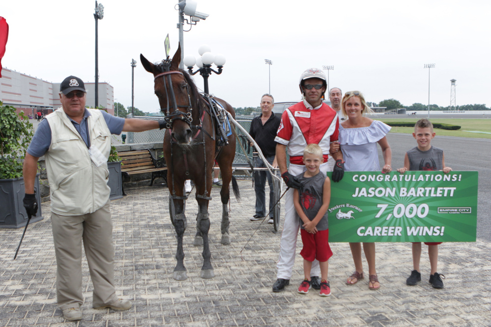 Jason Bartlett, in red an white, stands with his wife and kids after winning his 7,000th career race last Sunday at Yonkers Raceway in Yonkers, New York. Bartlett is a Windsor native and Erskine Academy graduate.