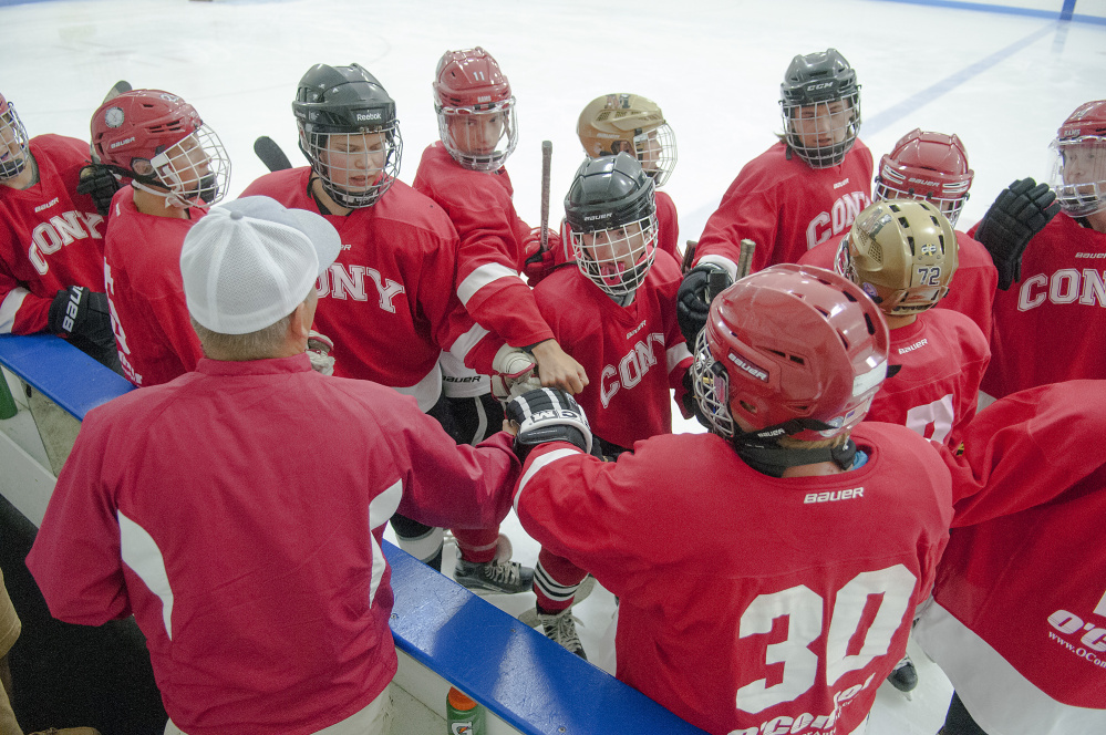 Coach Shawn Johnson, bottom left, rallies his Cony team before a game against Gardiner on Friday at the Camden National Bank Ice Vault in Hallowell.