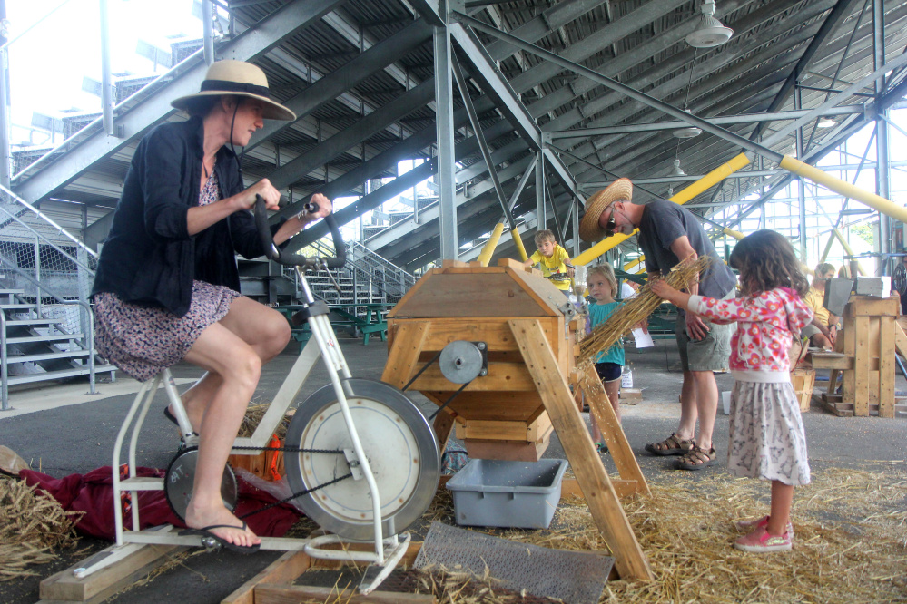 Emily Vogler, of Westport, Mass., works a wheat thresher Saturday with her 4-year-old daughter, Lucia Yoder, at the annual Artisan Bread Fair at the Skowhegan fairgrounds.