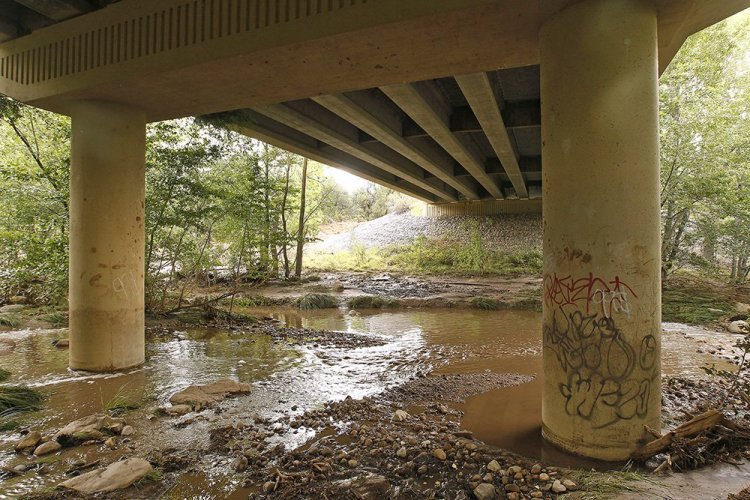 The receding floodwaters of the East Verde River flow under a bridge where at least one victim of a flash flood was found during a search and rescue operation in Payson, Arizona, Sunday.