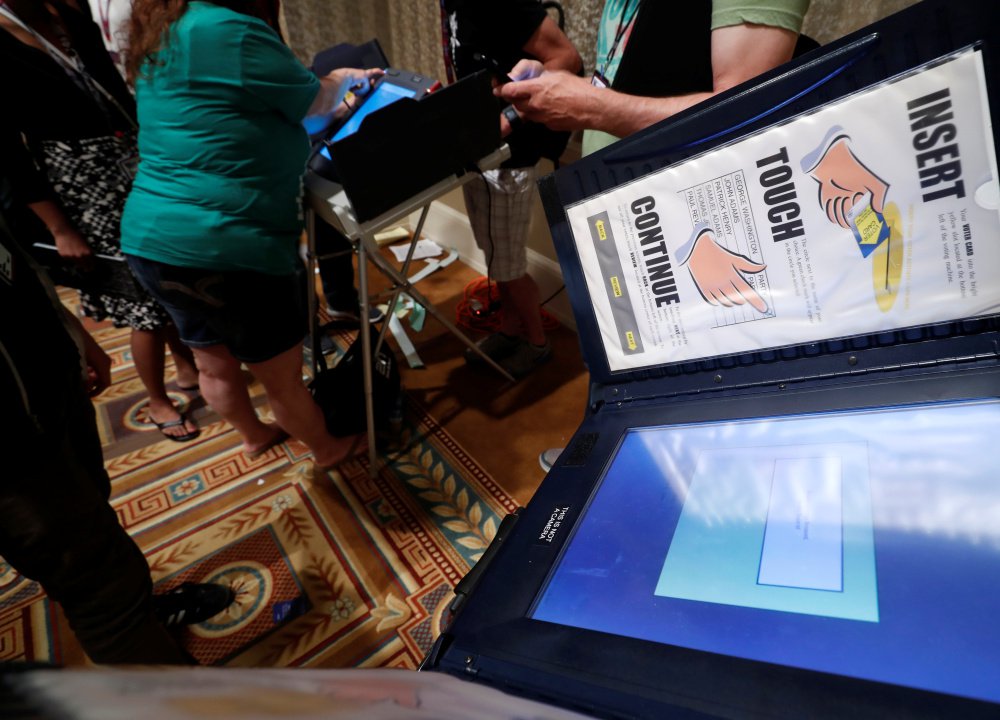 Hackers look over voting machines in a Voting Machine Hacking Village during the Def Con hacker convention in Las Vegas last week. The annual display of hacking skills revealed that many of the machines offered little in the way of security.