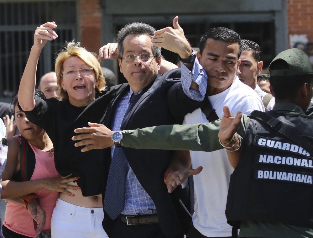 Venezuelan General Prosecutor Luisa Ortega Diaz, left, is surrounded by loyal employees after she was barred from entering by security forces, outside of the headquarters in Caracas, Venezuela.