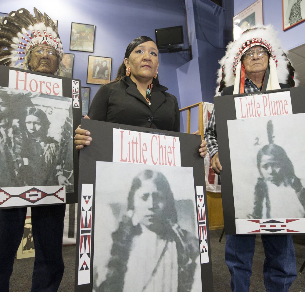 Yufna Soldier Wolf, center, of the Northern Arapaho, with tribal elders Mark Soldier Wolf, left, and Crawford White Sr., right, hold pictures of the three Arapaho children buried at the Carlisle Indian School, now the Army War College.