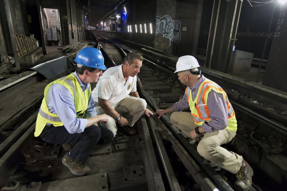 ConEd CEO John McAvoy, left, Gov. Andrew Cuomo, center, and an infrastructure company official examine tracks during a media tour of a section of the New York City subway system.