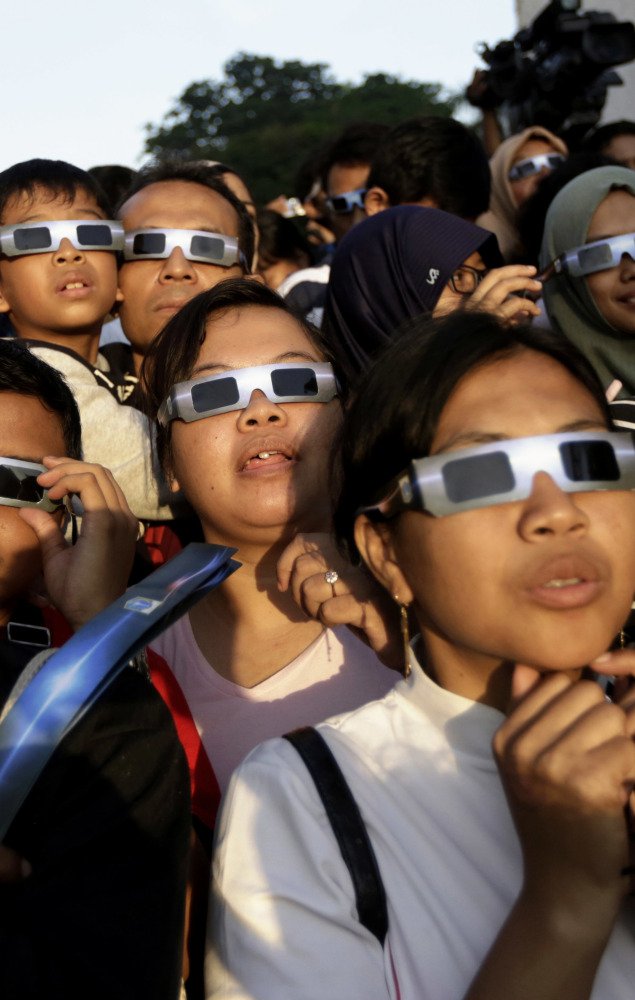 People wearing protective glasses look up at the sun to watch a solar eclipse in Jakarta, Indonesia, in 2016.