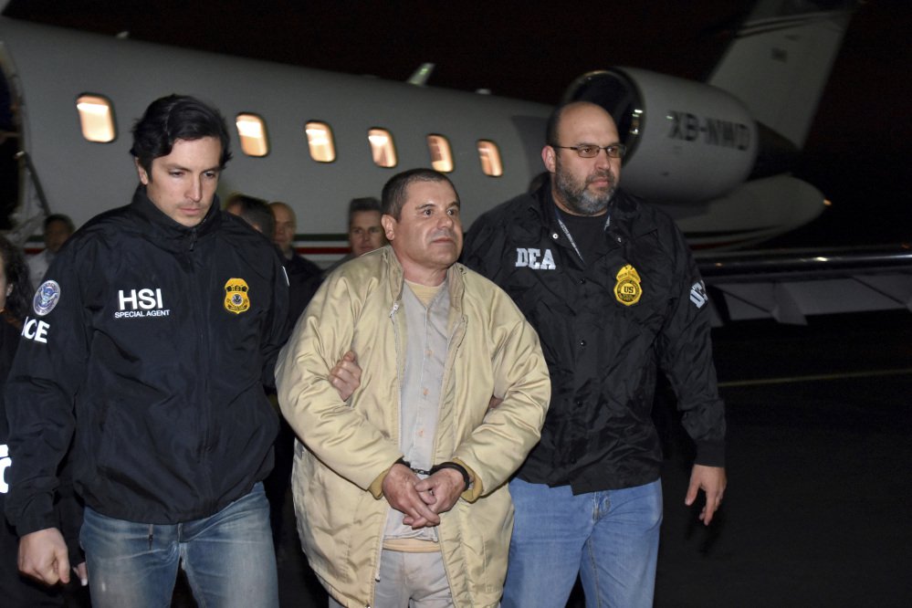 Authorities escort Joaquin "El Chapo" Guzman from a plane at an airport in New York in January. Guzman is seeking to have his public defenders replaced by private lawyers, but questions remain about how they will get paid.