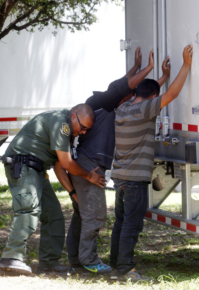 Border Patrol officer pats down several of the men that were found with a group of immigrants in a tractor-trailer in Edinburg, Texas.
