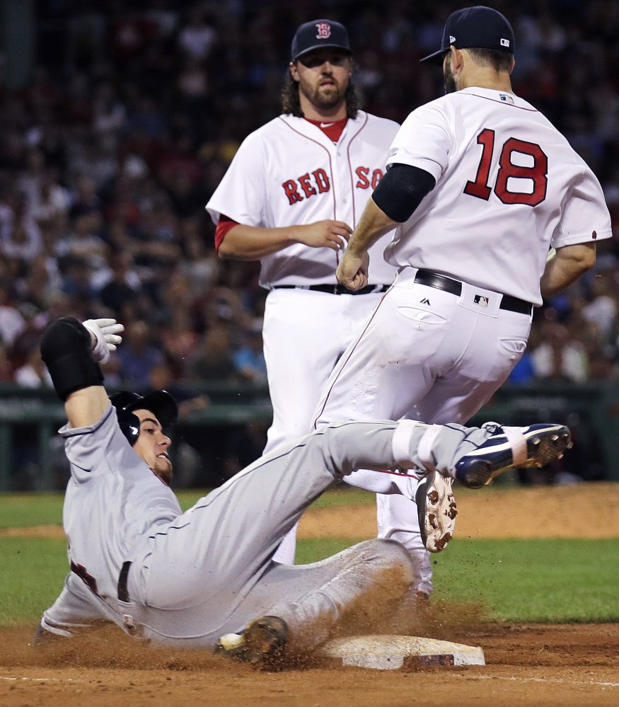 Cleveland Indians' Bradley Zimmer,  left, slides as he is forced out by Red Sox first baseman Mitch Moreland (18) on a ground-out during the seventh inning. Boston relief pitcher Heath Hembree, center, looks on.