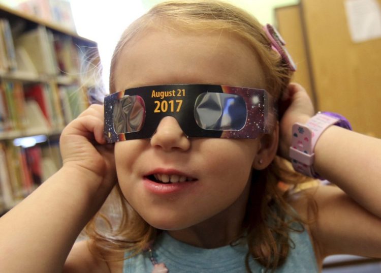 A girl tries on eclipse glasses at a library in Kings Mountain, N.C., on Wednesday. Glasses were being given away while they lasted.