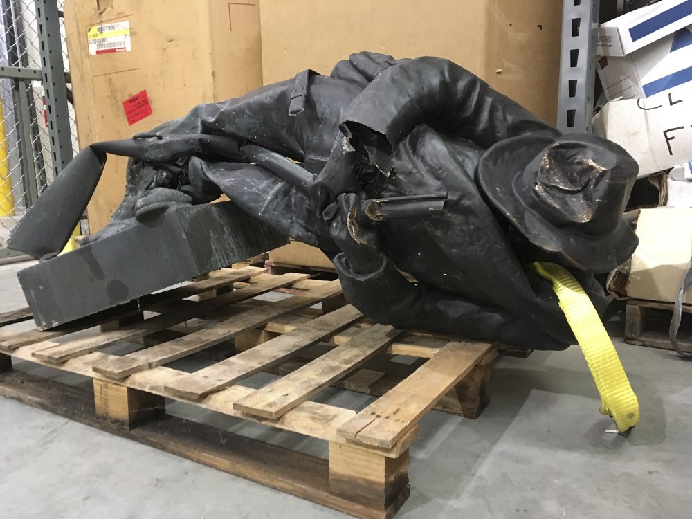 A damaged nearly century-old Confederate statue lies on a pallet in a warehouse in Durham, N.C., Tuesday. Investigators are working to identify and charge protesters who toppled the Confederate statue in front of a North Carolina government building, the sheriff said Tuesday. The Confederate Soldiers Monument, dedicated in 1924, stood in front of an old courthouse building that serves as local government offices.