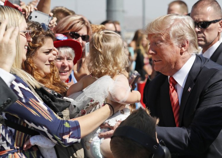 President Trump holds a baby as he greets supporters after arriving in Reno, Nev., on Wednesday.