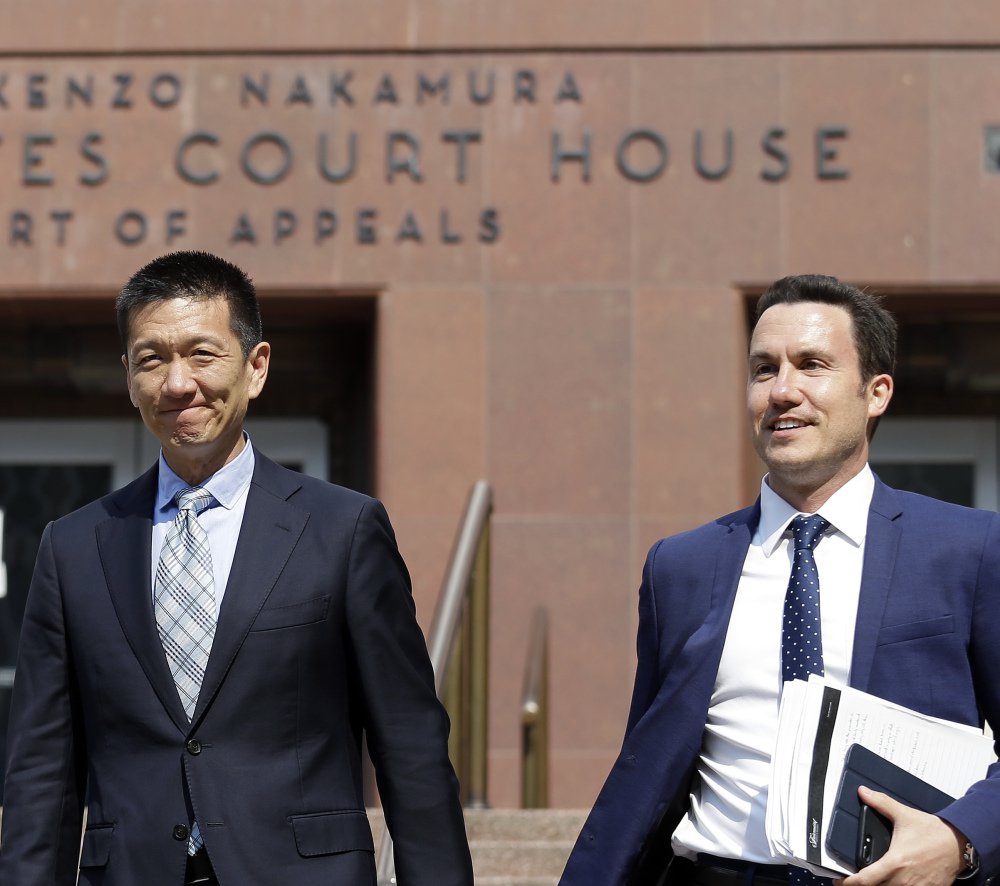 Hawaii Attorney General Doug Chin, left, smiles as he leaves a federal courthouse with assistant Joshua Wisch after appearing there Monday in Seattle.