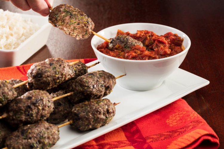 Lamb and Kalamata olive sausages are formed by hand, then skewered for cooking. Serve them with a minted tomato sauce.