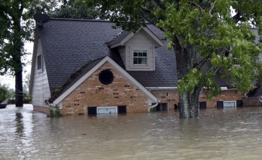 A home sits surrounded by floodwaters following heavy rains from Tropical Storm Harvey in Spring, Texas. Just 17 percent of homeowners in the counties suffering from Harvey flood damage have flood insurance, according to analysis of FEMA data.