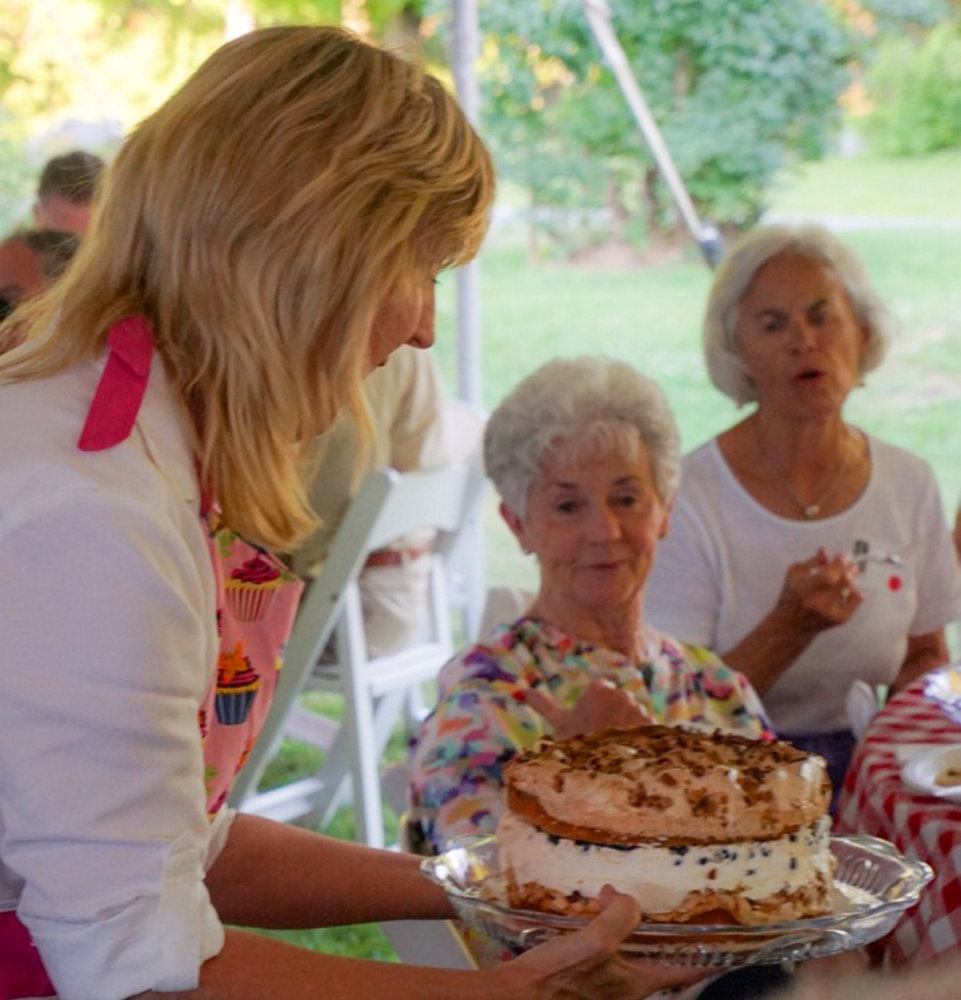Terri Wells, of Wiscasset, displays Connie's Favorite Birthday Cake to guests at Lincoln County Historical Association's Kermess at Pownalborough Court House. Linda Belmont considers making a bid.