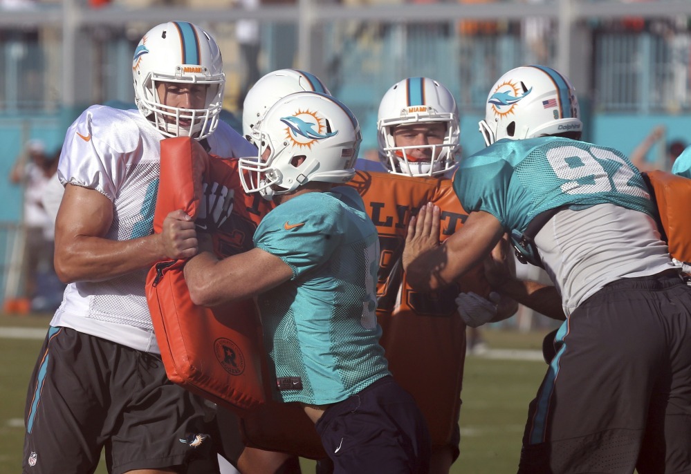 Miami Dolphins John Denney (92) and Trevor Reilly (57) hit pads during training camp Wednesday in Davie, Florida.