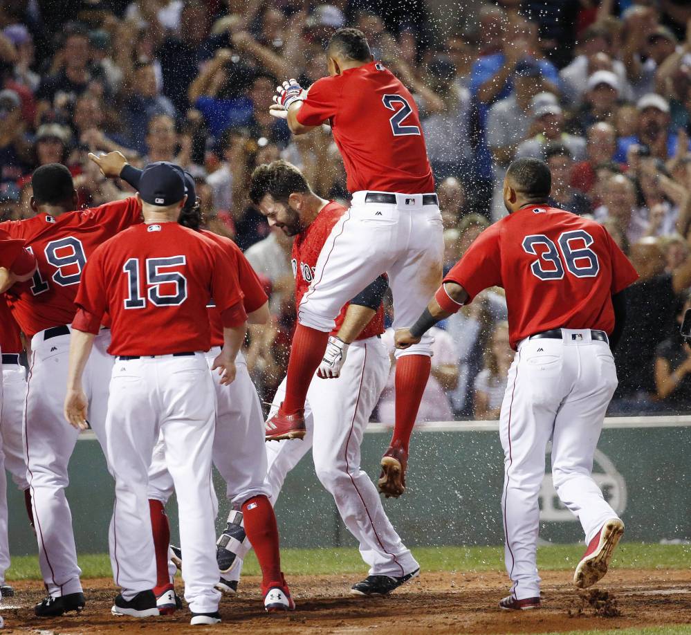 Boston Red Sox shortstop Xander Bogaerts (2) jumps as Mitch Moreland, center behind, crosses home plate on his walkoff home run during the 11th inning Friday against the Chicago White Sox in Boston.