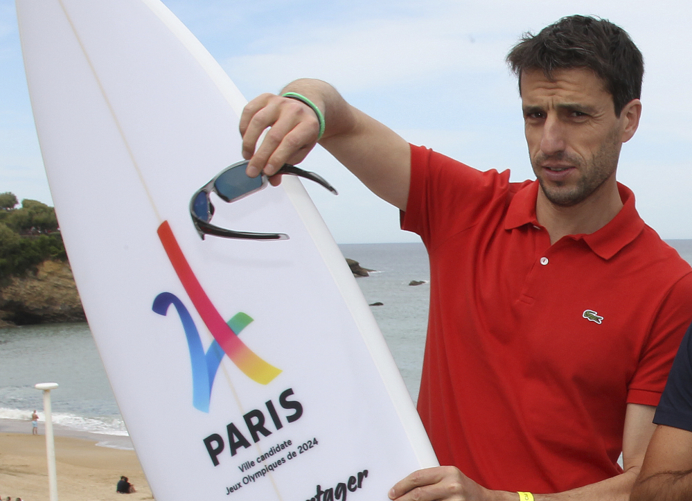 Tony Estanguet, French canoe champion and co-president of the Paris candidacy for the 2024 Olympics and Paralympic Games, poses with a surfboard reading "Paris candidate city Olympic Game 2024" during World Surfing Games in Biarritz, southwestern France last month.