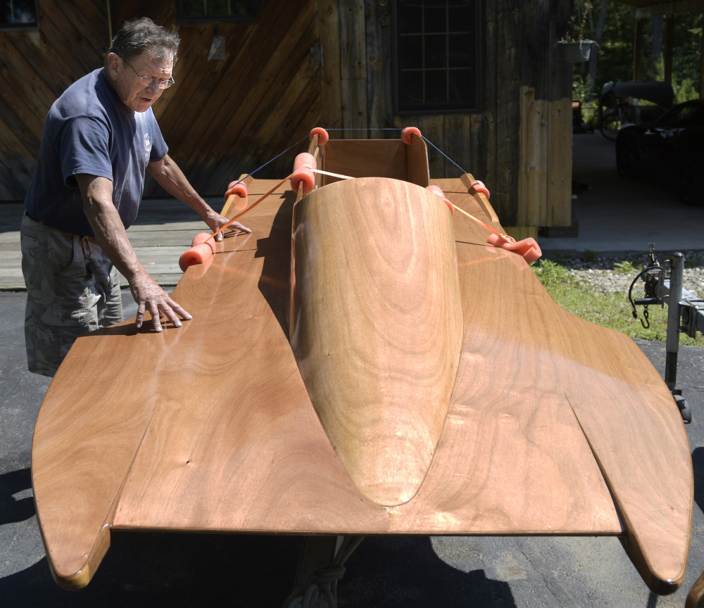 Alex Poliakoff inspects the repaired wooden hull of one of his racing boats on Wednesday at his shop in Bowdoinham. Poliakoff is returning to racing the crafts.