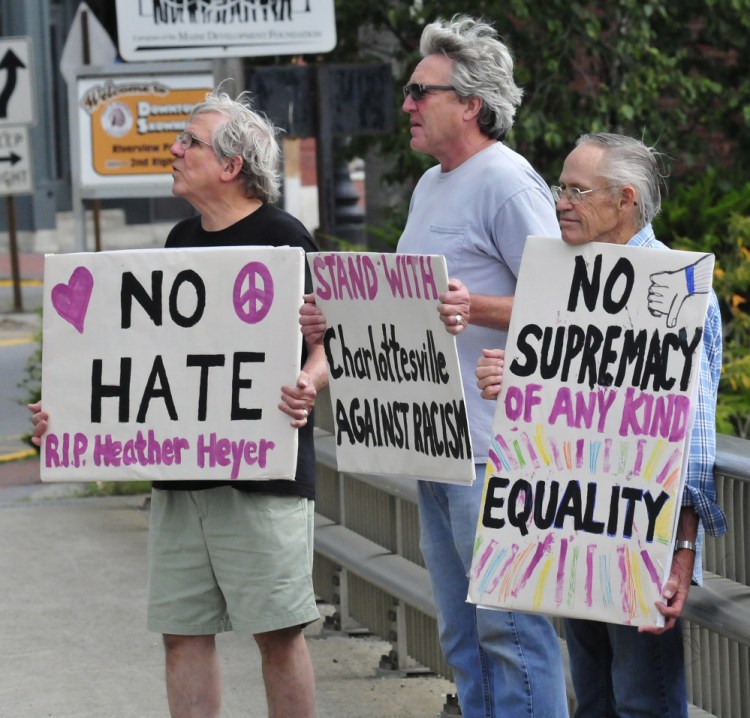 Protesters with Stand with Charlottesville Against White Supremacy hold signs against racism Sunday as motorists pass by in Skowhegan. From left are Mark Roman, Greg Williams and Dale Riddle.