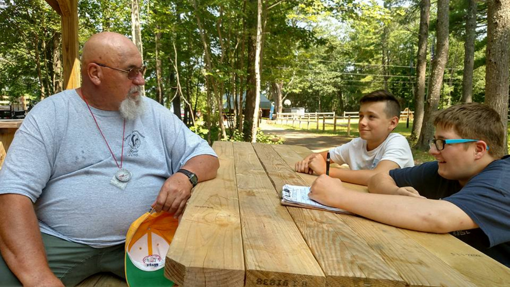 Ken Flagg, of Strong, left, being interviewed by Boy Scout Reporters Braden Mayo, center, and Ben Lamontagne, right, both of Oakland, at Camp Bomazeen in Belgrade.