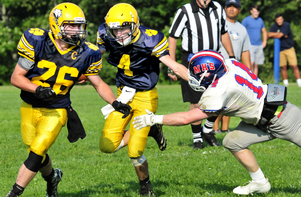 Mt. Blue's Noah Bell, center, evades a Messalonskee player during a scrimmage Monday in Oakland.