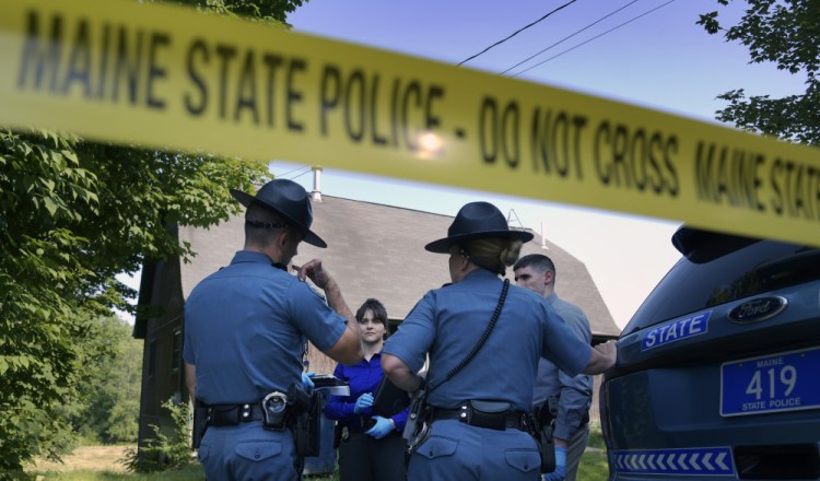 State troopers and detectives confer Monday outside a residence in Litchfield where a man was reportedly shot.