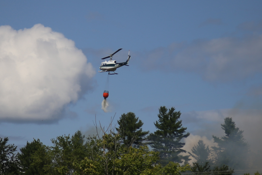 A Maine Forest Service helicopter drops water on a fire off Overlook Drive in Hallowell Friday. The helicopter first pulled water from the Kennebec River and then dropped it on the fire.