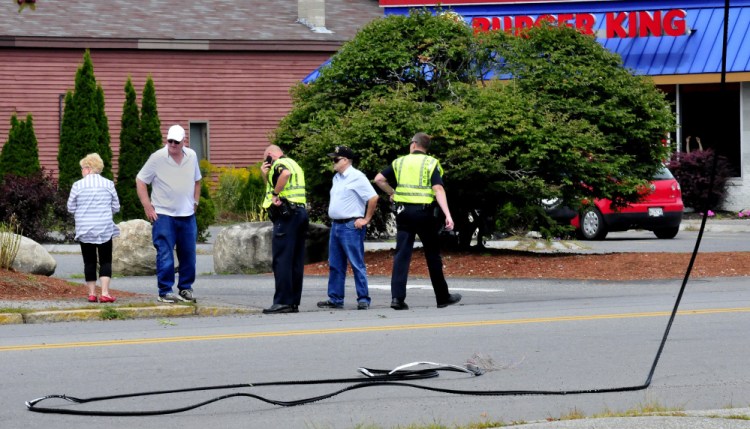 Waterville police interview witnesses near the site where two trucks are believed to be involved in hitting and snapping wires across College Avenue in Waterville on Tuesday.