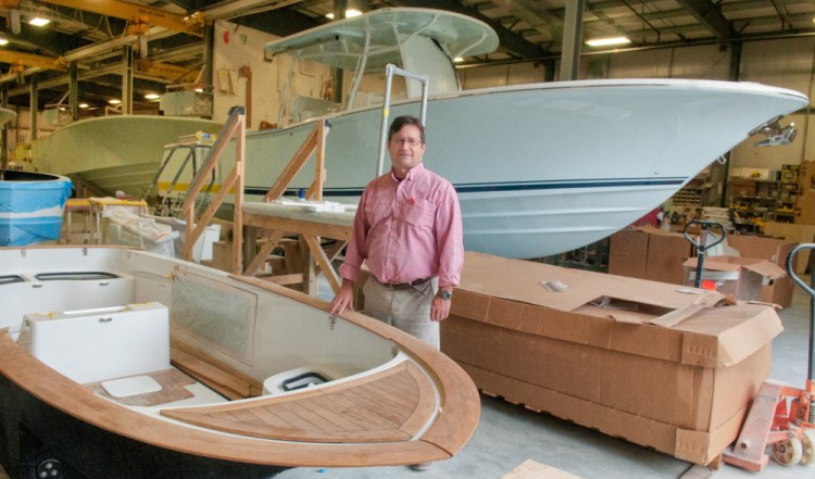 Southport Boats Vice President and General Manager George Menezes stands between a 16-foot Carbon Craft yacht tender, front, and 33-foot Southport center console boat Tuesday at Southport in Augusta, the day an expansion and sale was announced.