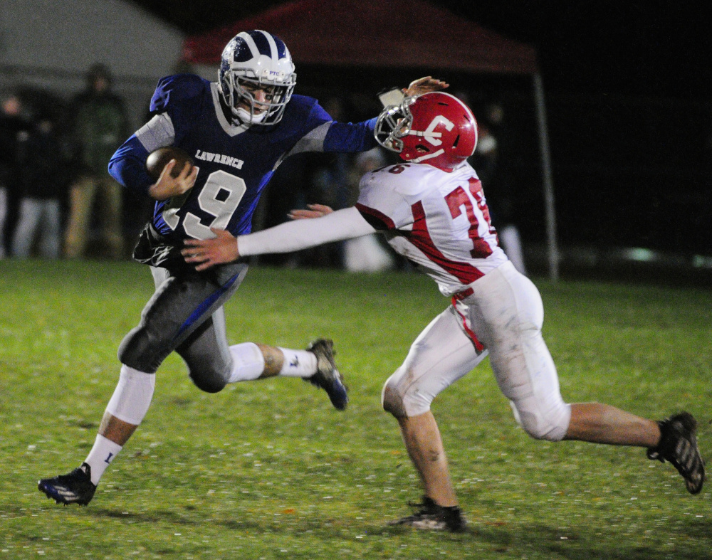 Lawrence running back Braden Ballard, left, stiff arms Cony defender Nic Mills during a Pine Tree Conference B quarterfinal game last season in Fairfield.