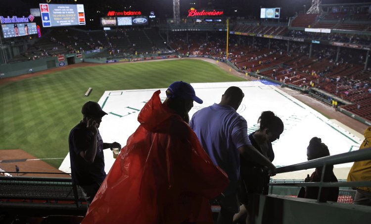 Fans leave Fenway Park after Wednesday's game between the Red Sox and Cleveland Indians was postponed due to heavy rain and thunderstorms.