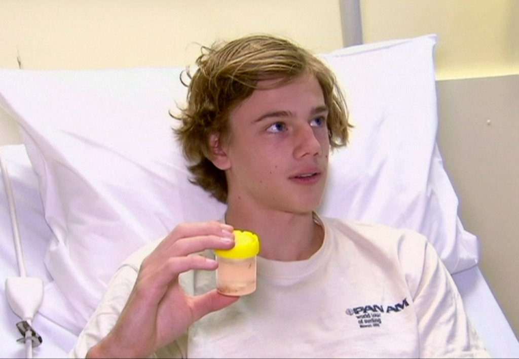 In this image made from video, Sam Kanizay, 16, holds a jar with sea creatures in it while speaking at a hospital where he was being treated, in Melbourne, Australia, on Monday. Kanizay walked out of the water with his feet and ankles covered in what looked like hundreds of little pin holes that were bleeding profusely. 