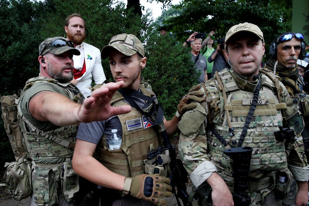 Heavily-armed white supremacist militia members surround a supporter after he scuffled with a counter demonstrator in Charlottesville, Virginia on August 12.