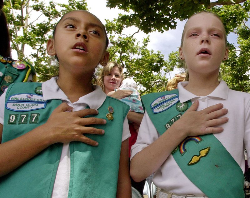 FILE - In this Monday, June 14, 2004 file photo, Santa Clara County Girl Scouts of America members Viris Rios, 10, left, and Madeline Hurst, 10, center, recite the Pledge of Allegiance during the 20th Annual Flag Day Ceremony at the Santa Clara County Government Center in San Jose, Calif. It's been 100 years since Juliette Gordon Low recruited the first scouts in Georgia. Low's original registration book from March of 1912 shows 102 recruits. Now there are 2.3 million active Girl Scouts nationwide. (AP Photo/Paul Sakuma, File)