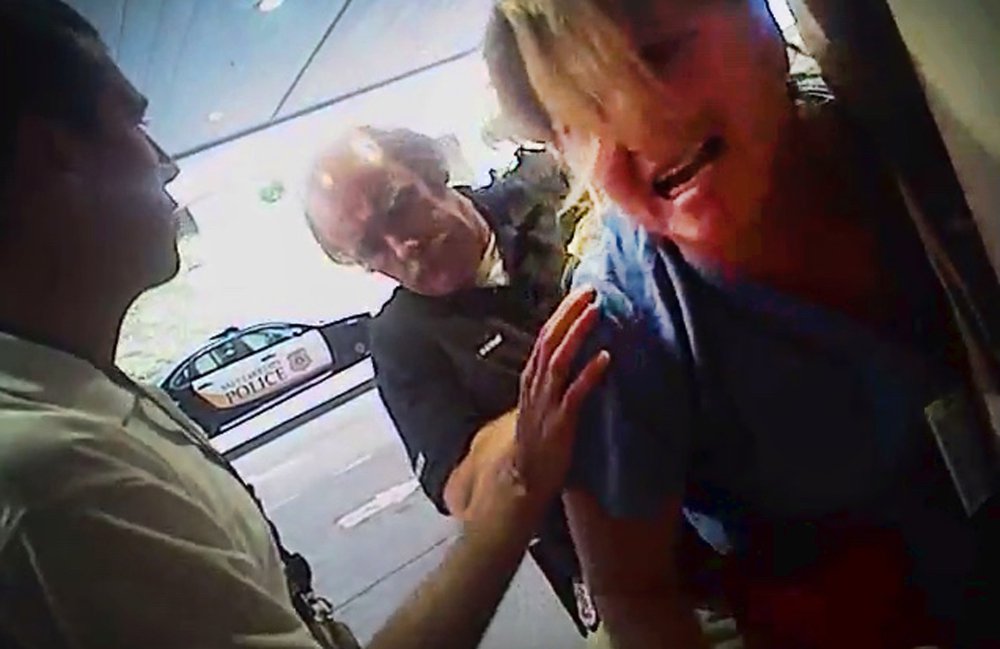 In this July 26 frame grab from a police body camera, nurse Alex Wubbels is handcuffed by a Salt Lake City police officer at University Hospital in Salt Lake City. Above, Wubbels, right, looks on during an interview with her attorney.