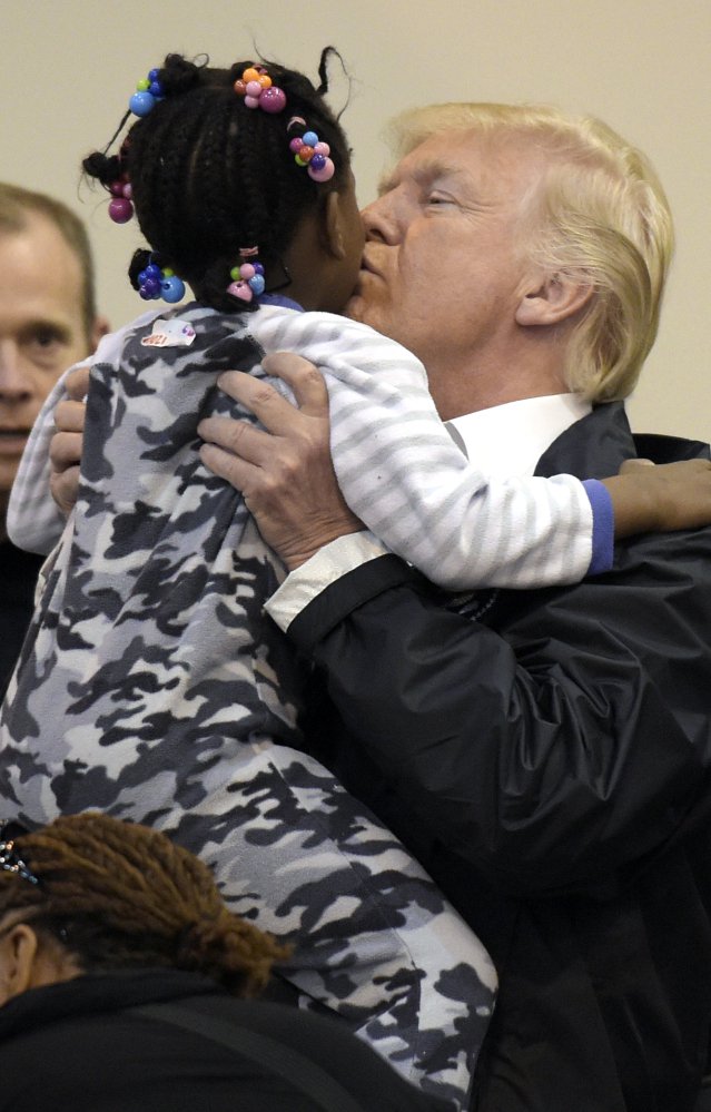 President Trump lifts a little girl and gives her a kiss as he and Melania Trump meet people impacted by Hurricane Harvey during a visit to the shelter at the NRG Center in Houston, Texas, on Saturday.