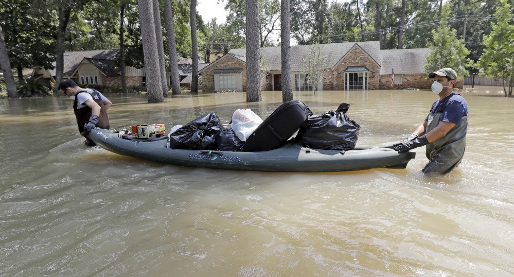 Gaston Kirby, left, is helped by his friend Juan Minutella on Monday after gathering the last of his belongings from his flooded home in the aftermath of Harvey.