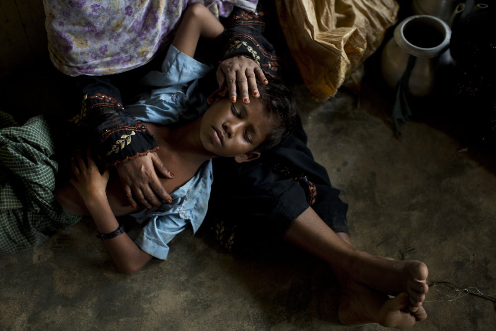 A Rohingya woman comforts her exhausted son as they take shelter at a refugee camp in Bangladesh after having just arrived from the Myanmar side of the border.