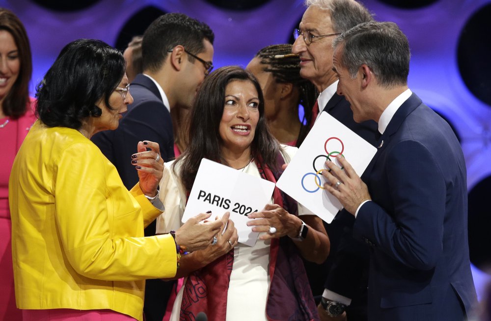 Paris Mayor Anne Hidalgo, center, speaks with Los Angeles Mayor Eric Garrett, right, and Los Angeles International Olympic Committee member Anita DeFrantz, left, in Lima, Peru on Wednesday where Los Angeles (2028) and Paris (2024) were named to play host for the Summer Olympic games.