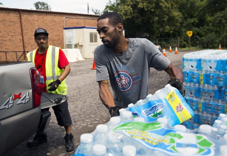 Shawn Jones, right, and Tony Price distribute bottled water last month in Flint, Mich.
