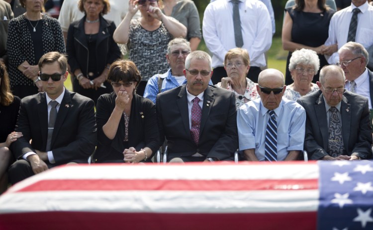 From left, Capt. Ben Cross' brother, Ryan Cross, his  mother, Valerie Cross, and his father, Robert Cross, along with other family members gather in front of Ben Cross' casket as he is laid to rest. Ryan Cross told the Press Herald the family has not received a call or letter from President Trump.