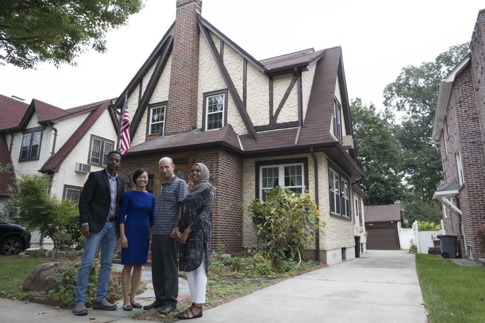 Abdi Iftin, left, of Somalia, Uyen Nguyen, second from left, of Vietnam, Eiman Ali, right, of Somalia born in Yemen, and Ghassan al-Chahada, of Syria pose for a photo outside President Trump's boyhood home in the Jamaica Estates neighborhood of the Queens borough of New York.