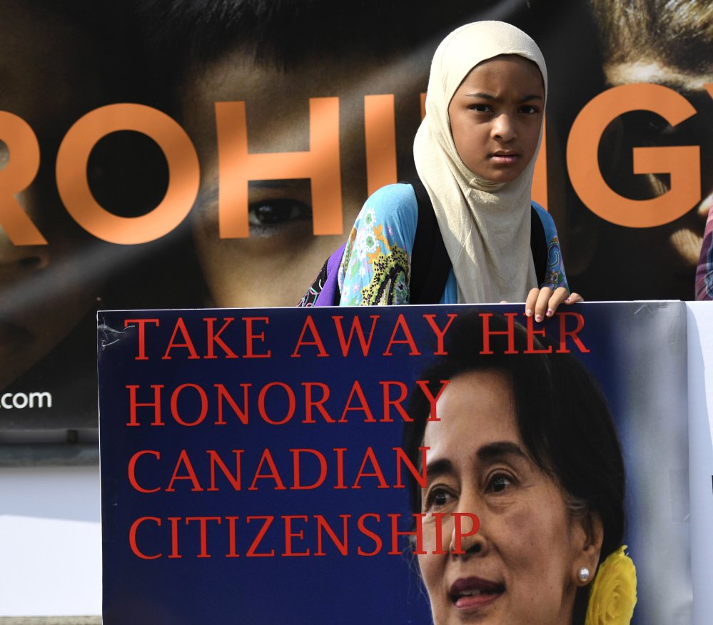 A girl holds a sign calling for the removal of the honorary Canadian citizenship of Myanmar leader Aung San Suu Kyi, during a rally in Ottawa on Sunday.