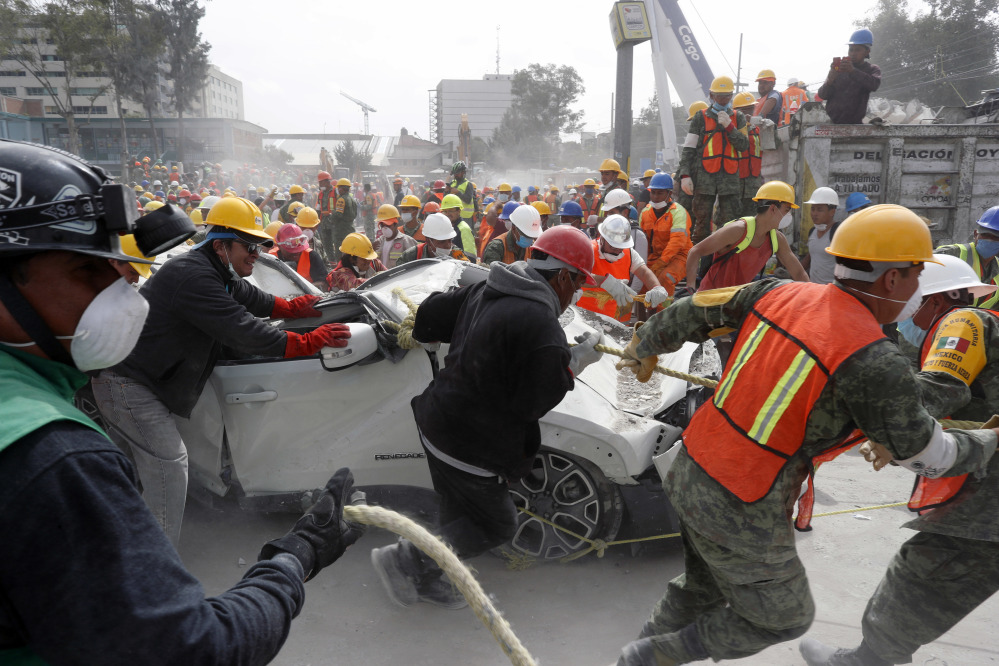 Volunteers and soldiers remove a destroyed vehicle from the parking lot of a four-story clothing factory in Mexico City that was brought down by Tuesday's 7.1-magnitude earthquake.