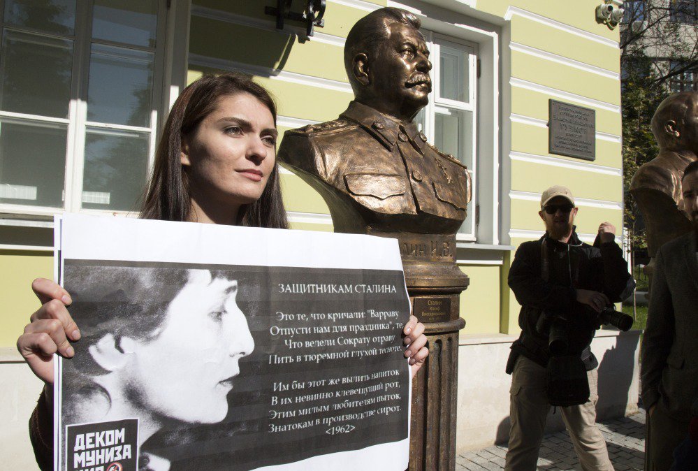A woman protests the unveiling of Josef Stalin's bust in Moscow. The poster carries the verses of poet Anna Akhmatova denouncing those who try to whitewash Stalin.